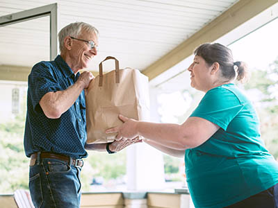 Courier Delivering Groceries to Senior Man on Porch