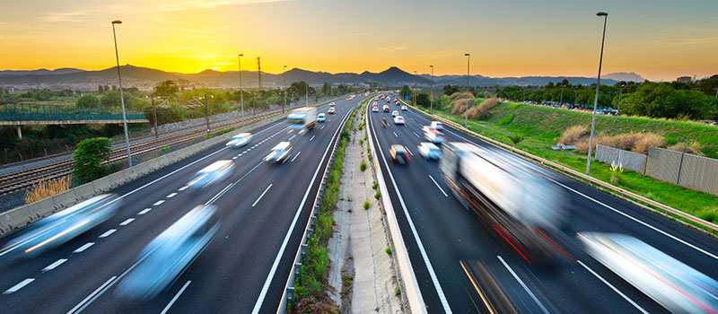 A motion-blurred image of a busy freeway with last mile delivery trucks | OneRail
